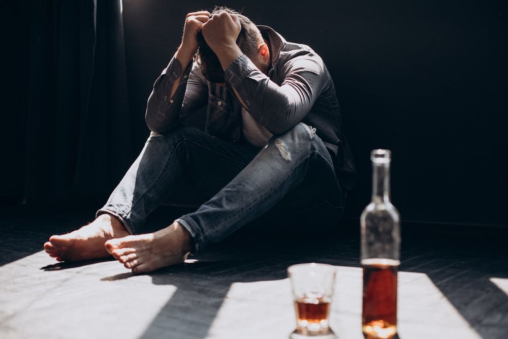 man depressed drinking whiskey